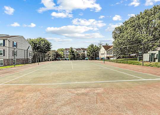 A tennis court surrounded by houses and trees.