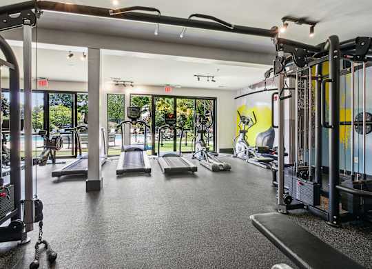 A gym with a variety of equipment including treadmills, weights, and exercise machines.