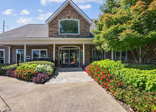 A building with a grey roof and a glass window is surrounded by green bushes and trees at Elme Marietta Apartments, Marietta, GA