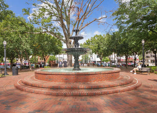 A fountain in the middle of a brick plaza surrounded by trees  at Elme Marietta Apartments, Marietta, GA