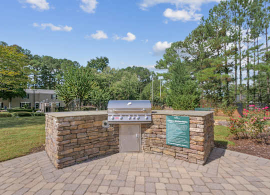 A stone grill area with a sign and a green board.
