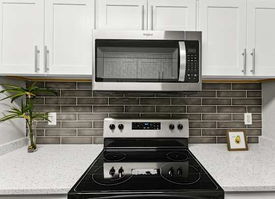 A modern kitchen with a black stove top and a white microwave above it.