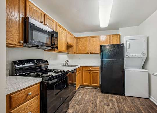 A kitchen with black appliances and wooden cabinets at Elme Watkins Mill, Gaithersburg