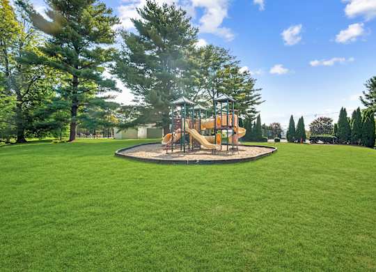 A playground with a swing set in the middle of a grassy area.