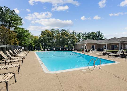A large outdoor swimming pool surrounded by lounge chairs at Elme Watkins Mill, Gaithersburg