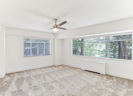 A room with a ceiling fan and a window with blinds.