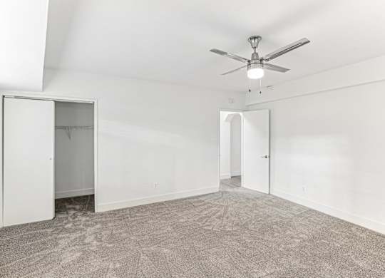 A room with a ceiling fan and carpeted floor.