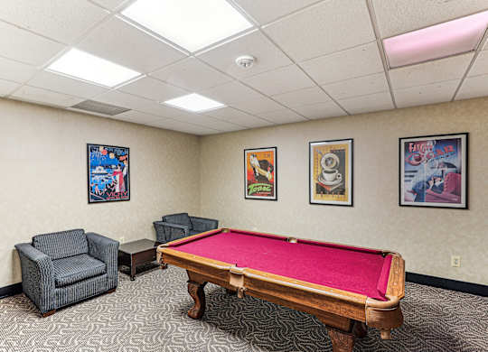 A room with a pool table and three framed pictures on the wall.