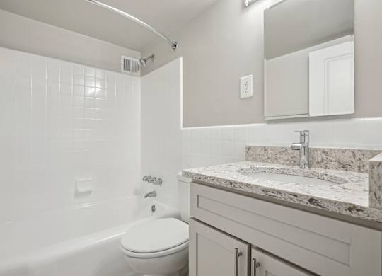 A white bathroom with a tub, toilet and sink at The Kenmore, Washington, 20015