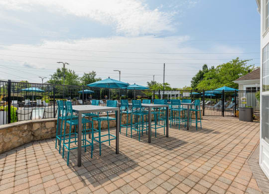 a patio with blue chairs and tables and umbrellas
