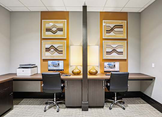A room with two desks and chairs, each with a computer and monitor  at The Paramount, Arlington, Virginia