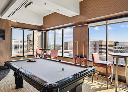 A pool table in a room with a view of the city.