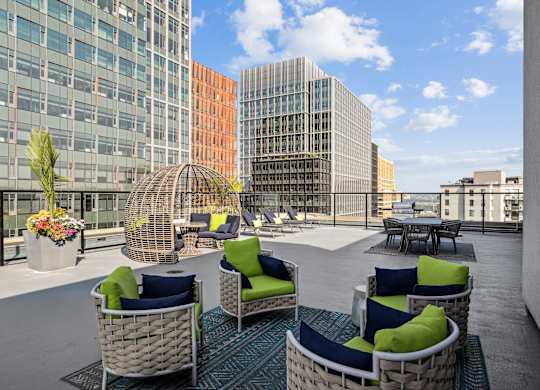 A patio with wicker chairs and tables with a view of the city.