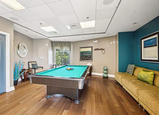 A pool table is in the middle of a room with a couch and a chair at Riverside Apartments, Alexandria, Virginia