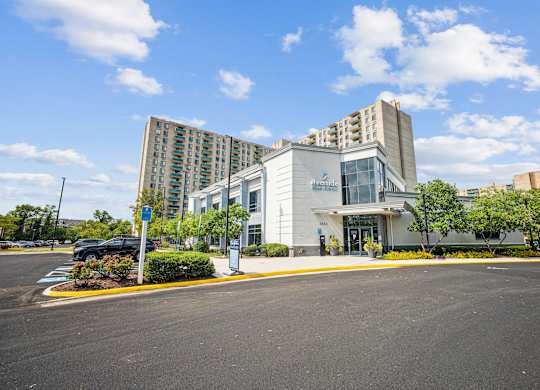A modern building with a glass entrance and a parking lot in front at Riverside Apartments, Alexandria, Virginia