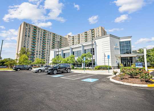 A parking lot in front of a building with a blue sign at Riverside Apartments, Alexandria, Virginia