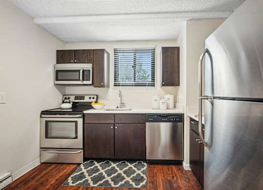 A kitchen with a stainless steel refrigerator, microwave, oven, and sink at Riverside Apartments, Alexandria, Virginia