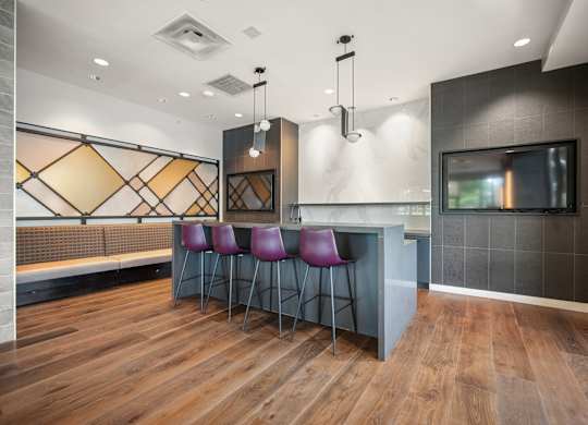 A modern bar area with purple chairs and a wooden floor at Riverside Apartments, Alexandria, Virginia