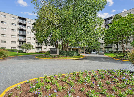 A view of a roundabout with a sign in the middle and apartment buildings  at Roosevelt Towers, Falls Church, VA