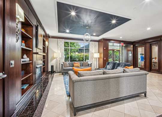 A modern living room with a grey sofa and a chandelier  at Roosevelt Towers, Falls Church, VA