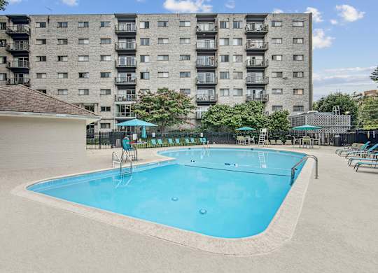 A large blue swimming pool in front of a tall apartment building  at Roosevelt Towers, Falls Church, VA