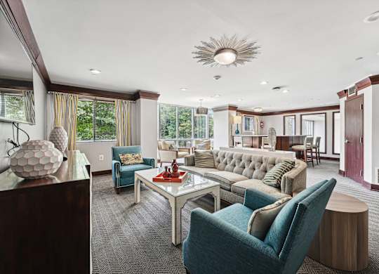 A modern living room with a blue chair and a glass table  at Roosevelt Towers, Falls Church, VA