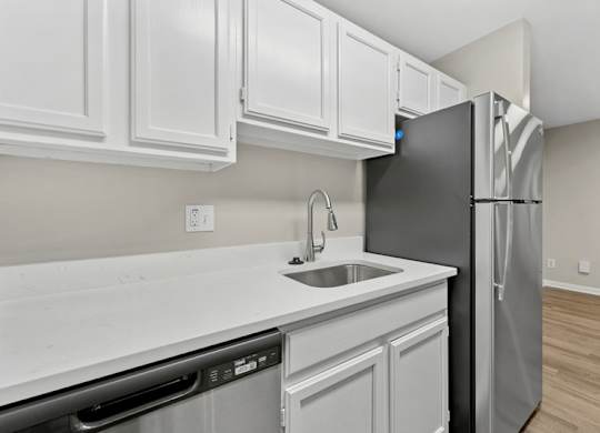 A kitchen with a black refrigerator and white cabinets.