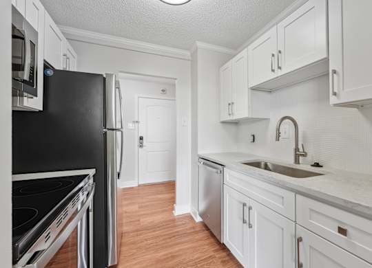 A kitchen with white cabinets and a black refrigerator  at Riverside Apartments, Alexandria, Virginia