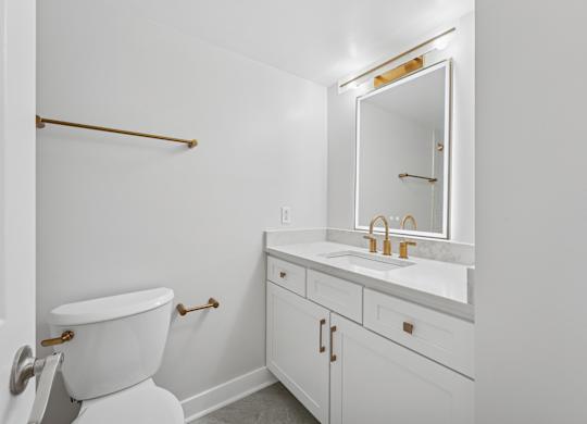 A white bathroom with a toilet, sink and mirror  at Riverside Apartments, Alexandria, Virginia