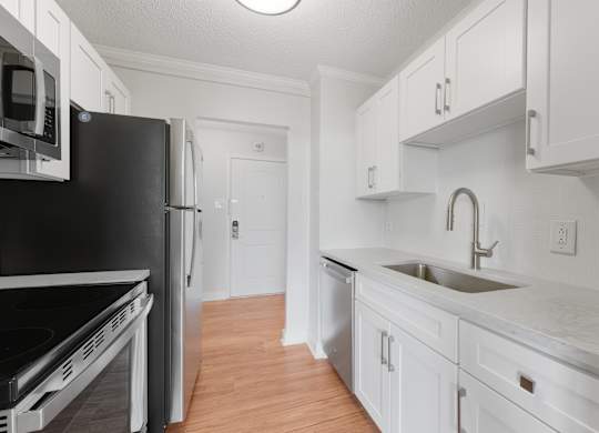 A kitchen with white cabinets and a black fridge at Riverside Apartments, Alexandria, Virginia