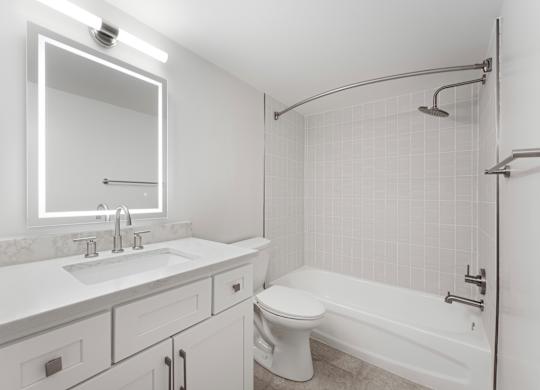 A white bathroom with a sink, mirror, toilet and bathtub.