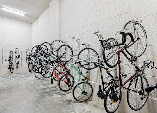 A row of bicycles are parked in a white room.