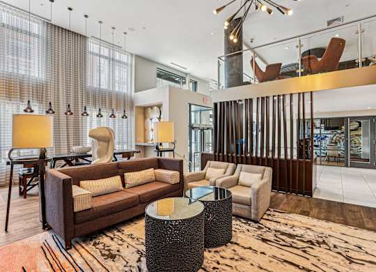 A modern living room with a brown sofa and a glass wall at The Maxwell Apartments, Arlington