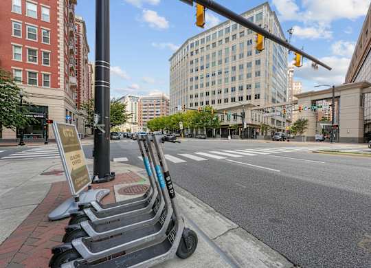 A row of scooters are parked on the sidewalk.
