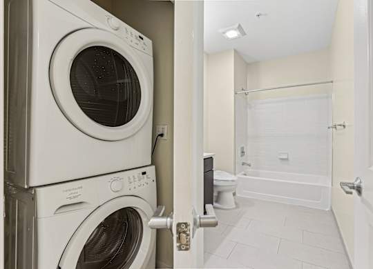 A white washing machine and dryer stacked on top of each other in a laundry room.