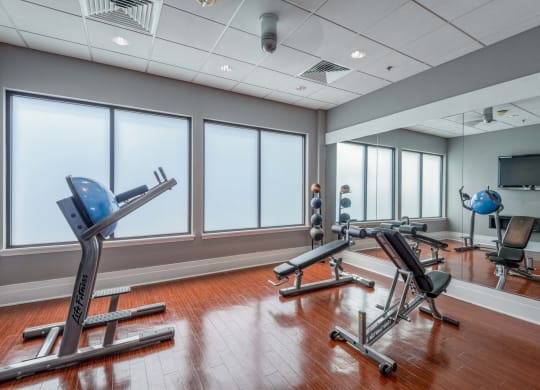a fitness room with exercise machines and windows