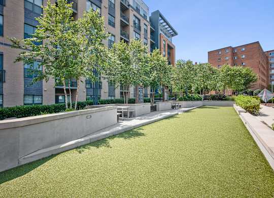 A grassy area in front of a building with trees.