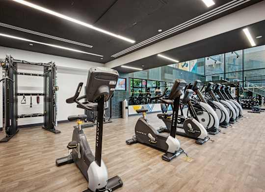 A gym with a variety of exercise equipment including treadmills, stationary bikes, and weight machines.