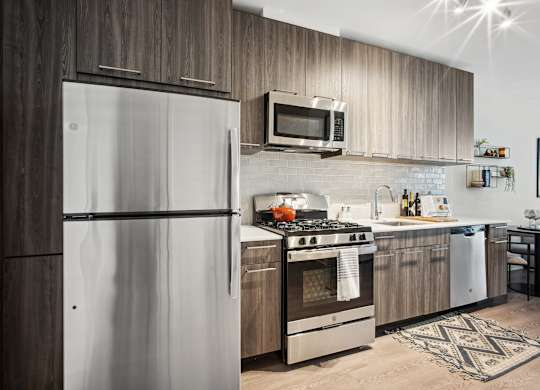 A modern kitchen with a refrigerator, oven, and microwave.