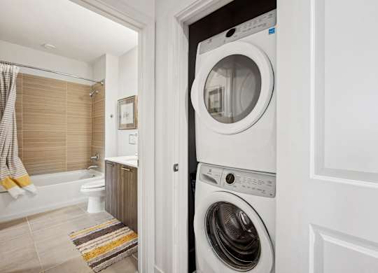 A white washing machine is in a small laundry room.