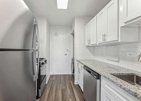 A kitchen with a stainless steel refrigerator and a granite countertop.