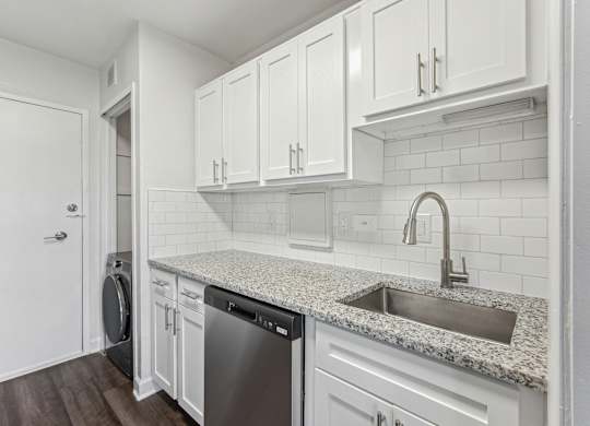 A kitchen with white cabinets and a granite countertop at Wellington Apartments, Arlington, Virginia