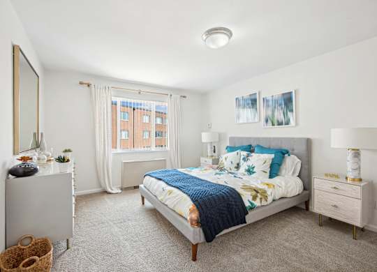 A bedroom with a bed, nightstand, and window.