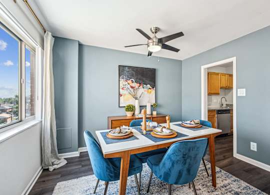 A dining room with a table set for two and a ceiling fan.