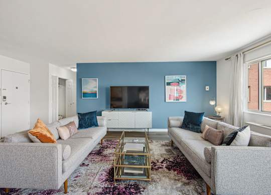 A living room with a grey couch, a coffee table, and a flat screen TV.