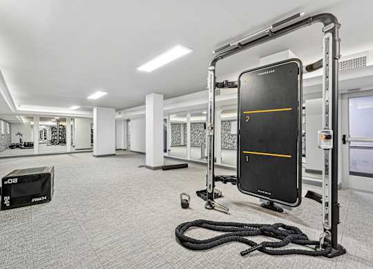 A gym with a rope, a bench, and a black screen with a yellow line.