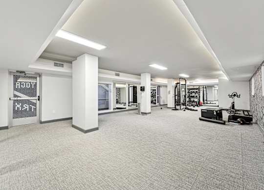 A spacious gym with a variety of equipment and a white color scheme at Wellington Apartments, Arlington, Virginia