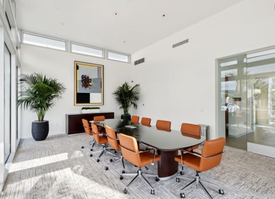 a conference room with a large table and orange chairs at The Max on Jefferson Apartments, California