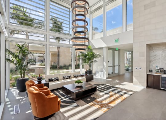 a lobby with a spiral staircase in the middle of a building with large windows at The Max on Jefferson Apartments, Murrieta, CA