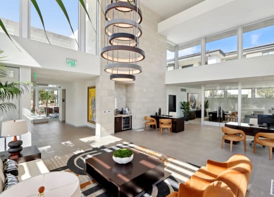 a living room with a large amount of windows and a table and chairs at The Max on Jefferson Apartments, California, 92562